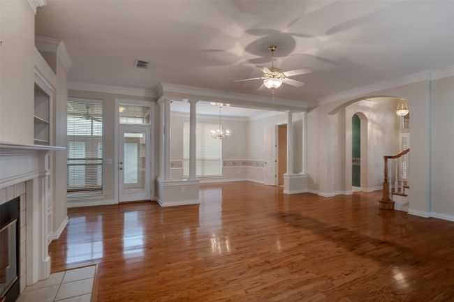 Unfurnished living room featuring a tile fireplace, arched walkways, a ceiling fan, crown molding, and light wood finished floors | Image 7