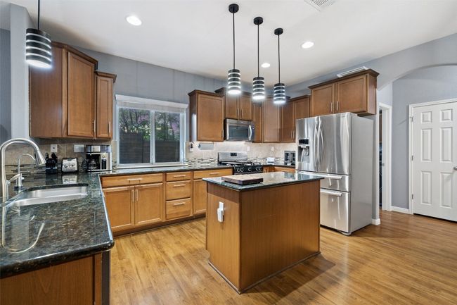 The kitchen boasts granite counters, stainless steel appliances including the refrigerator, center island plus the sink overlooks the back yard. | Image 9
