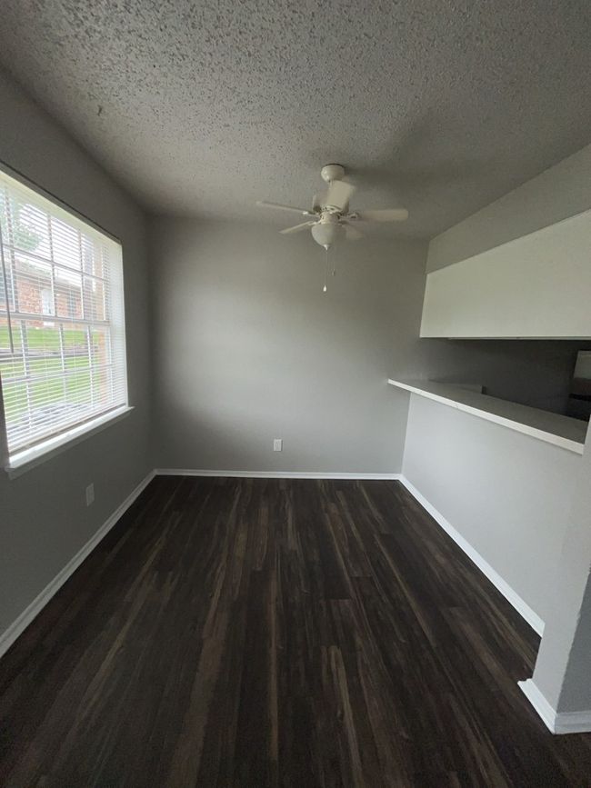 Empty room with dark wood finished floors, a textured ceiling, a ceiling fan, and baseboards | Image 7