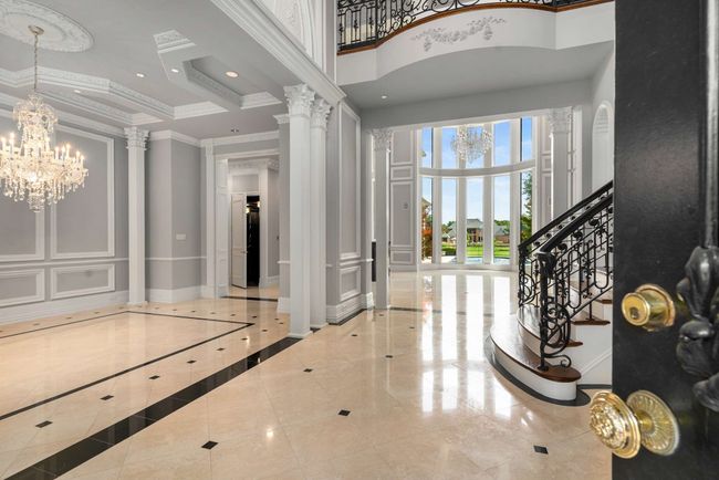 Entry features a towering ceiling, ornamental molding, chandeliers and grand stairway | Image 4