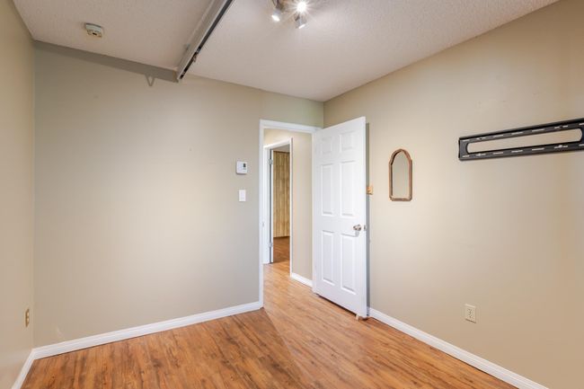 Bedroom featuring baseboards, a textured ceiling, and light wood-style floors | Image 32