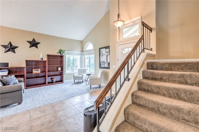 Stairs with tile patterned flooring, a textured ceiling, high vaulted ceiling, and baseboards | Image 23