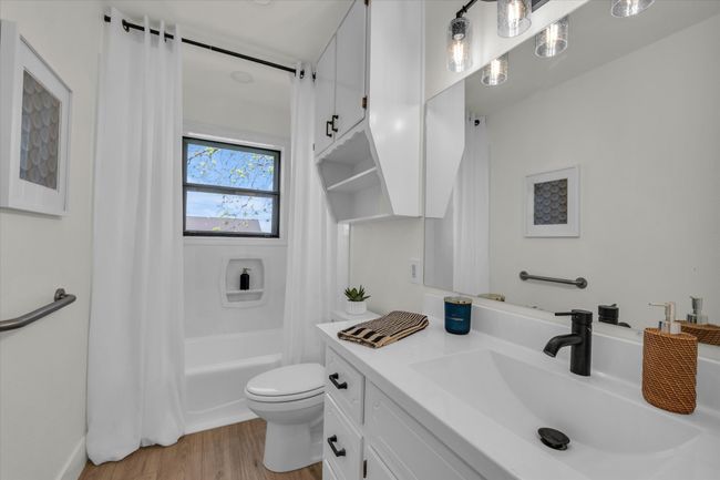 Full bathroom with toilet, shower / bath combo with shower curtain, vanity, and wood finished floors | Image 31