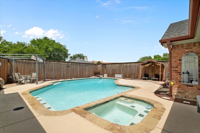 View of pool with a patio, a fenced backyard, and a pool with connected hot tub | Image 29