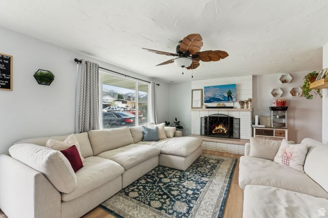Living room featuring wood finished floors, a brick fireplace, and a ceiling fan | Image 4
