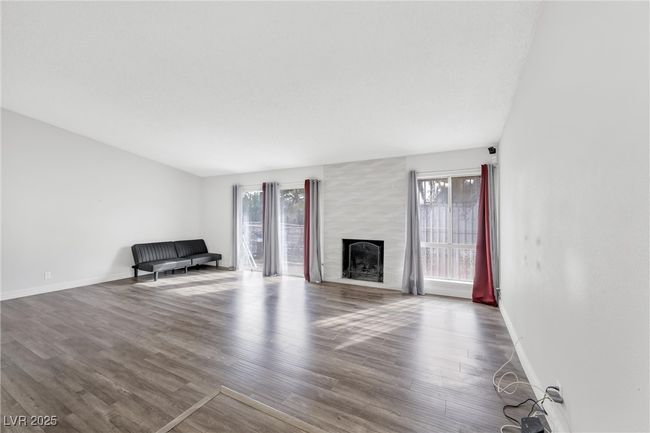 Unfurnished living room with a wealth of natural light, wood finished floors, and baseboards | Image 8