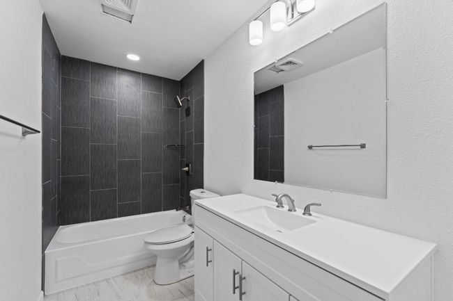 Bathroom featuring vanity, shower / bathtub combination, and marble look tile flooring | Image 20