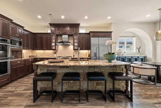 Kitchen featuring appliances with stainless steel finishes, wall chimney range hood, a sink, an island with sink, and a kitchen breakfast bar | Image 12