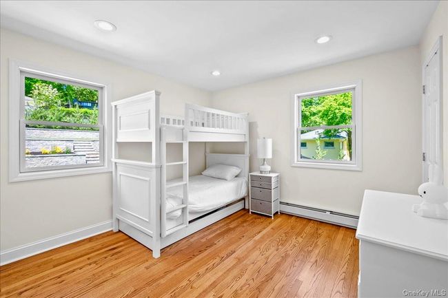 Bedroom featuring a baseboard radiator, multiple windows, light wood finished floors, and recessed lighting | Image 19