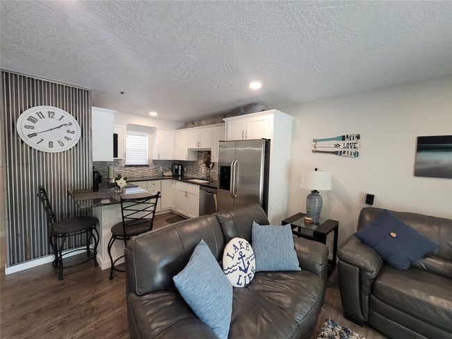 Living room with a textured ceiling, dark wood-type flooring, and sink | Image 6