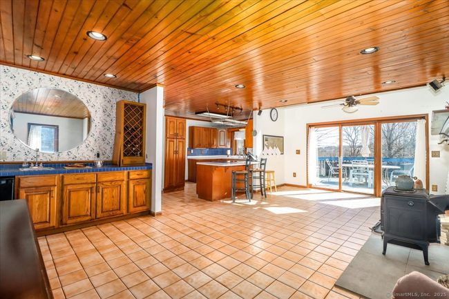 Light a cozy fire in the wood stove next to the kitchen in a family room with a wet bar and sliders to the back deck. | Image 21