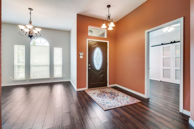 Foyer entrance featuring a chandelier, dark wood-type flooring, and a barn door | Image 7