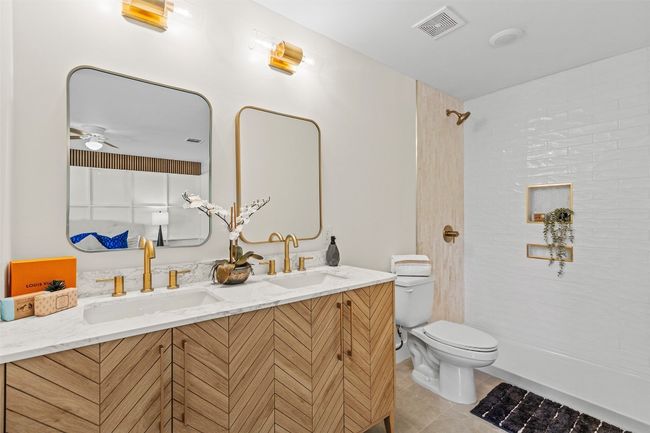 Full bath featuring toilet, double vanity, tile patterned floors, a shower, and ceiling fan | Image 23