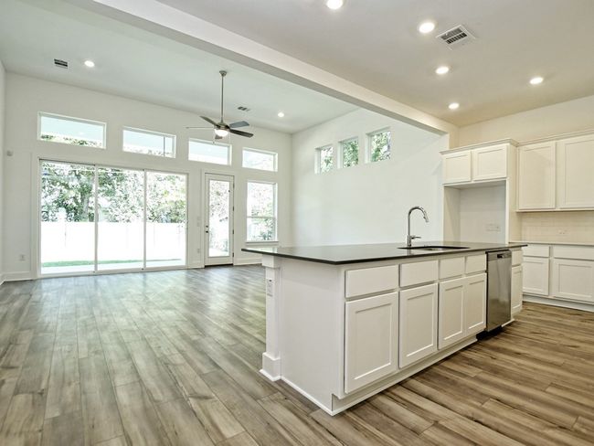 Kitchen with open floor plan, dark countertops, light wood finished floors, ceiling fan, and recessed lighting | Image 10