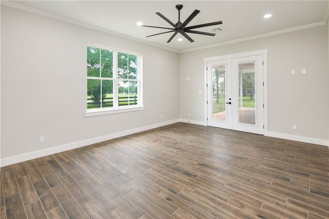 Empty room with french doors, ceiling fan, dark wood finished floors, crown molding, and recessed lighting | Image 11