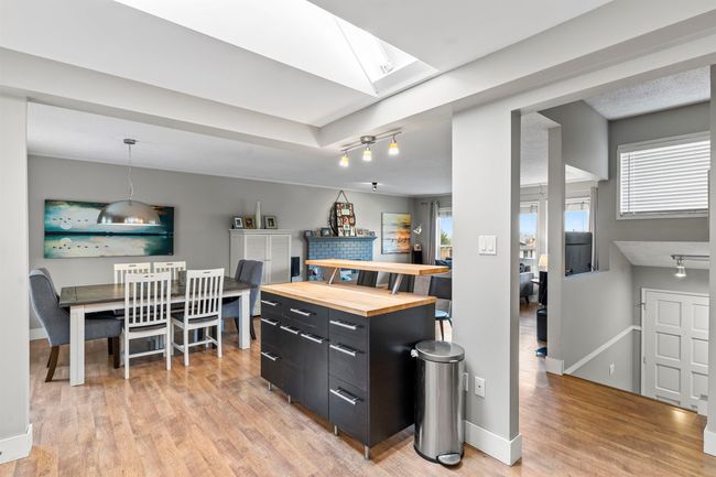 Kitchen featuring baseboards, dark cabinetry, light wood finished floors, wood counters, and a skylight | Image 10