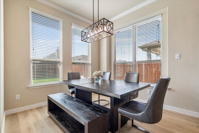 Dining space with a chandelier, ornamental molding, light wood-style flooring, and baseboards | Image 12