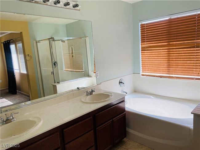 Bathroom with double vanity, a stall shower, a garden tub, and a sink | Image 15