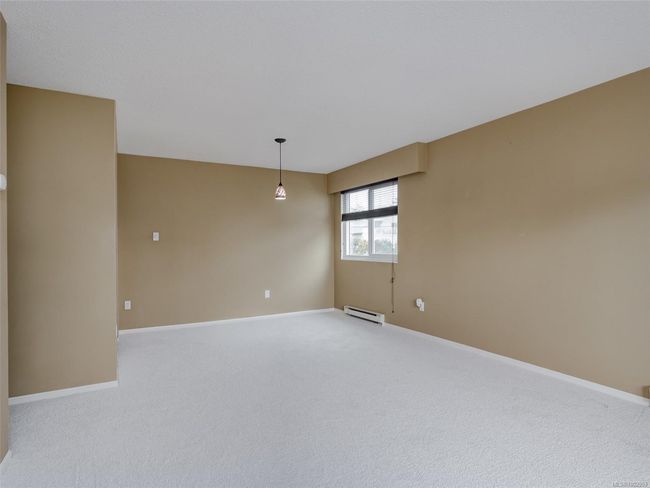 Empty room featuring a baseboard radiator and light colored carpet | Image 5