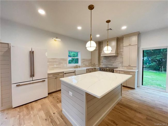 Example of the work we do. Not this house. Kitchen with tasteful backsplash, hanging light fixtures, a kitchen island, appliances with stainless steel finishes, and light hardwood / wood-style flooring | Image 10
