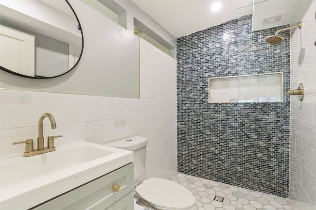 Bathroom featuring a tile shower, tile walls, and vanity | Image 12