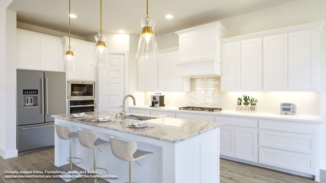 Kitchen with stainless steel appliances, light wood-style flooring, white cabinets, a sink, and a kitchen island with sink | Image 6