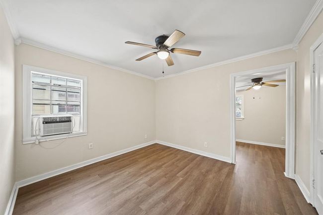 This beautiful Primary Bedroom includes vinyl plan floors, crown molding, a large window and a ceiling fan. | Image 12