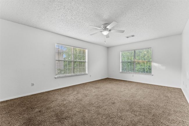 Carpeted spare room featuring a ceiling fan, healthy amount of natural light, a textured ceiling, and baseboards | Image 21