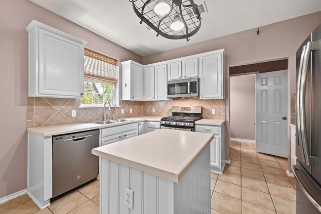 Kitchen with appliances with stainless steel finishes, white cabinetry, and light countertops | Image 13