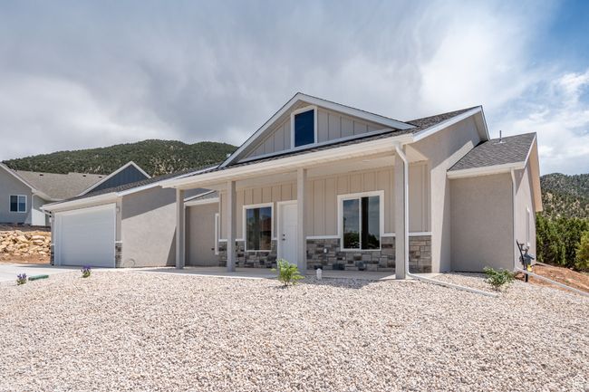 View of front facade featuring covered porch, board and batten siding, driveway, a garage, and roof with shingles | Image 5