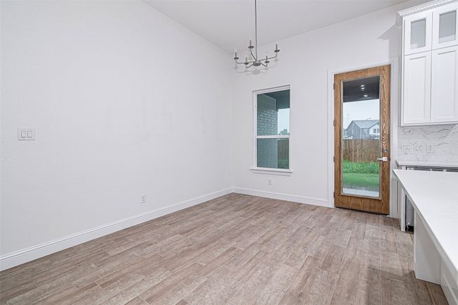 Unfurnished dining area with a chandelier, light wood finished floors, lofted ceiling, and baseboards | Image 12
