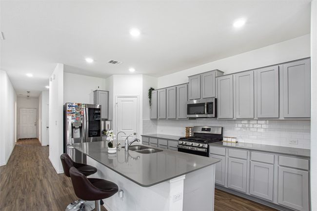 Kitchen with a kitchen breakfast bar, a sink, appliances with stainless steel finishes, gray cabinetry, and visible vents | Image 16