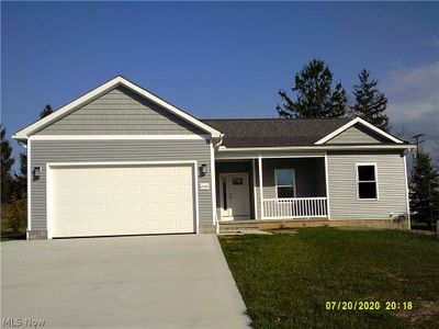 Ranch-style home featuring a front yard, a garage, and a porch | Image 1