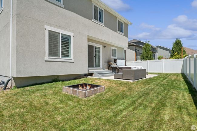 Back of property with an outdoor living space with a fire pit, a fenced backyard, stucco siding, a patio, and a residential view | Image 31