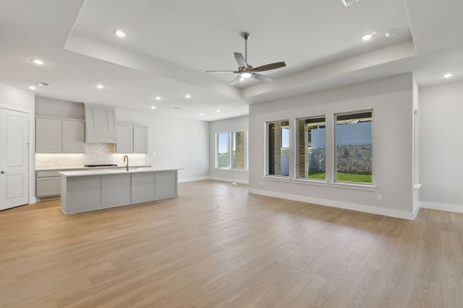 Kitchen with a raised ceiling, open floor plan, backsplash, recessed lighting, and ceiling fan | Image 10