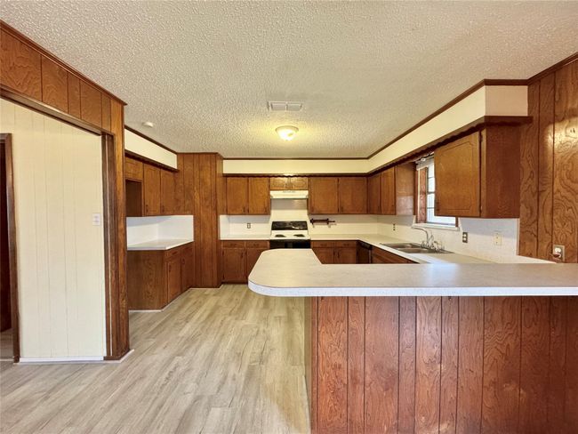 Kitchen featuring sink, electric range, kitchen peninsula, crown molding, and light wood-type flooring | Image 18