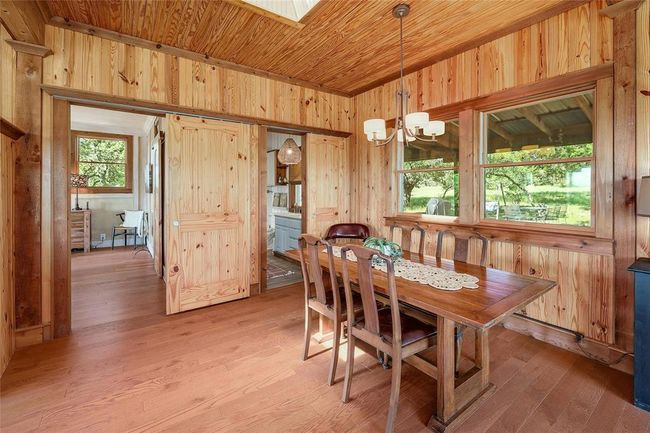 Dining space featuring wooden walls, vaulted ceiling, light wood-style floors, wood ceiling, and a notable chandelier | Image 11