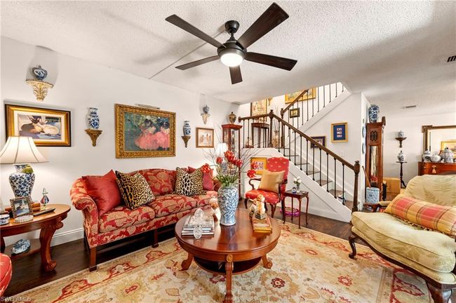 Living room featuring wood finished floors, a textured ceiling, a ceiling fan, and stairs | Image 8