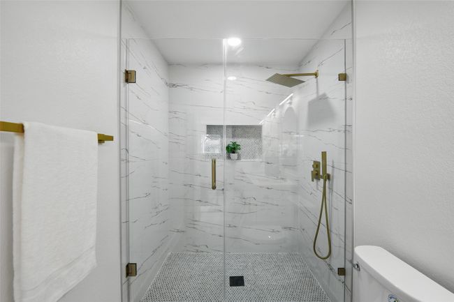Bathroom with toilet and a marble finish shower | Image 23
