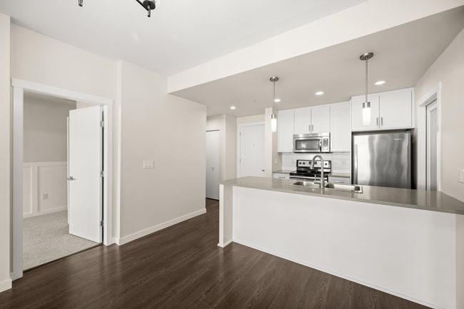 Kitchen featuring appliances with stainless steel finishes, dark wood-style flooring, white cabinets, recessed lighting, and hanging light fixtures | Image 15