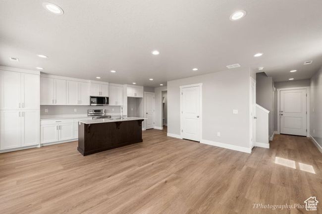 Kitchen featuring appliances with stainless steel finishes, recessed lighting, white cabinets, light wood finished floors, and light countertops | Image 7