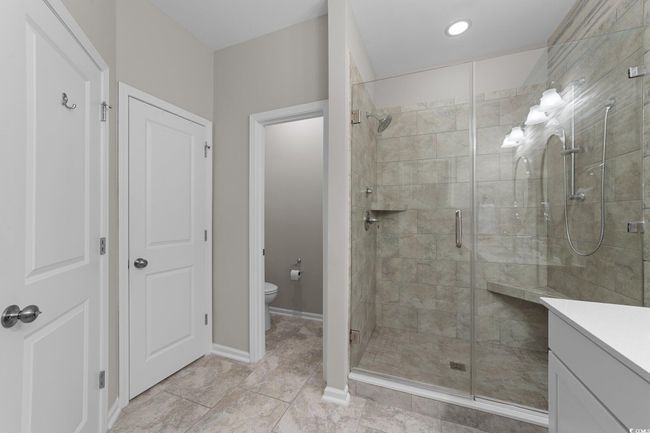 Full bathroom featuring a stall shower, toilet, vanity, tile patterned flooring, and baseboards | Image 18