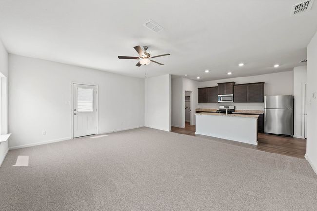 Unfurnished living room with dark colored carpet, recessed lighting, and a ceiling fan | Image 4