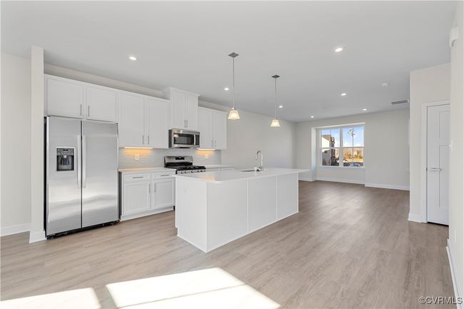 Kitchen with appliances with stainless steel finishes, light countertops, baseboards, white cabinets, and light wood-style flooring | Image 4