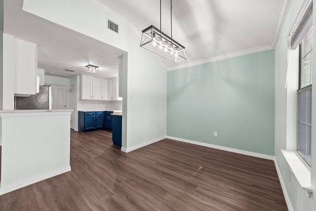 Unfurnished dining area with ornamental molding, dark wood-type flooring, a chandelier, and baseboards | Image 8