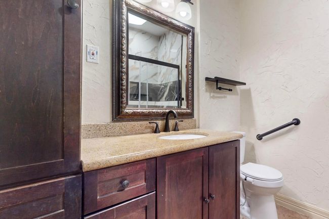 Bathroom featuring toilet, a textured wall, baseboards, and vanity | Image 29
