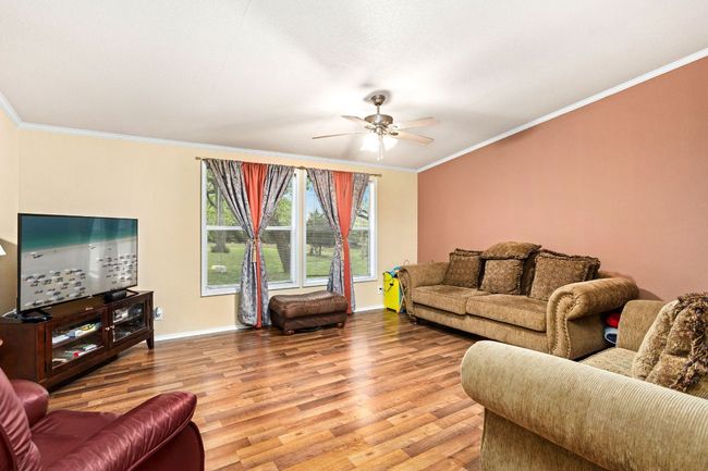 Living room featuring ornamental molding, baseboards, ceiling fan, and light wood-type vinyl flooring | Image 19