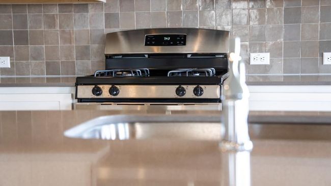 Kitchen view of backsplash, stainless steel gas stove, and white cabinetry | Image 14