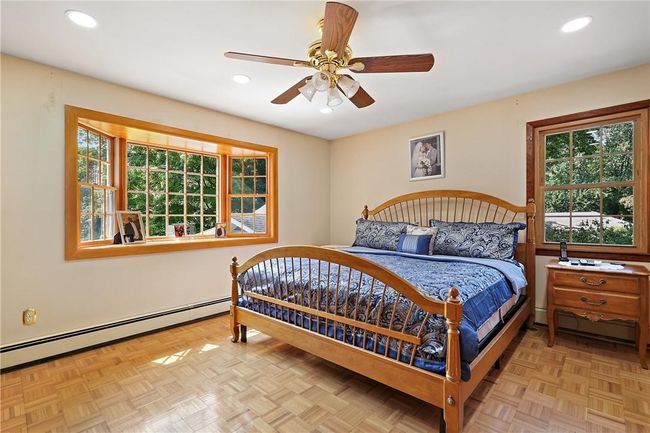 Bedroom with a baseboard radiator, light parquet flooring, and ceiling fan | Image 15
