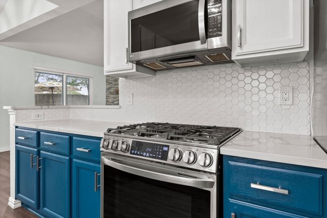 Kitchen featuring stainless steel appliances, blue cabinets, tasteful backsplash, and dark wood finished floors | Image 12
